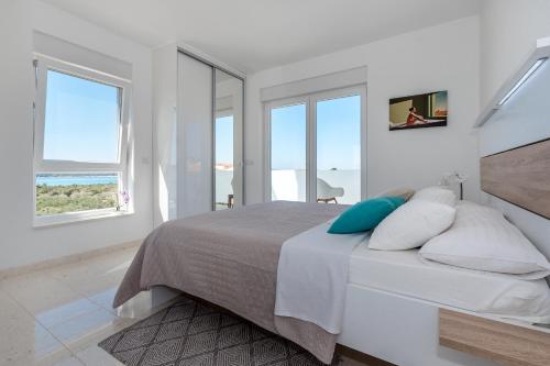 a white bedroom with a bed with windows at Villa Buzuk in Vodice