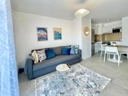 un salon avec un canapé bleu et une cuisine dans l'établissement Superbe appartement neuf entre mer et pins Wifi, à Argelès-sur-Mer