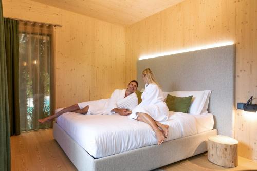 Ein Mann und eine Frau sitzen auf einem Bett in der Unterkunft TreeLodgy, The Tree House in Riva del Garda