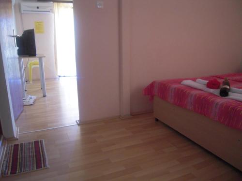 a bedroom with a bed with a red bedspread and a wooden floor at Lile Pestani Accommodation in Peštani