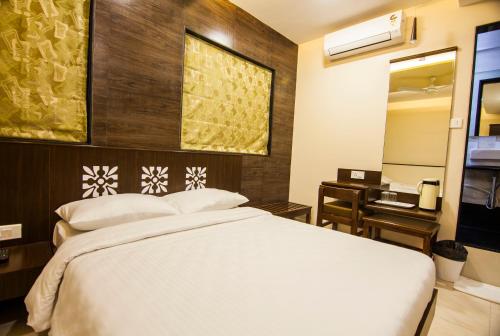 a bedroom with a bed and a desk and a mirror at City Guest House - Dadar in Mumbai