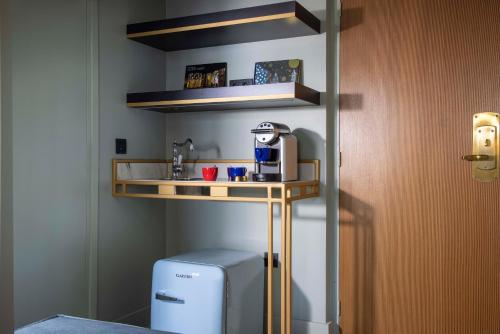 a small kitchen with a shelf next to a refrigerator at Les Jardins Du Luxembourg in Paris