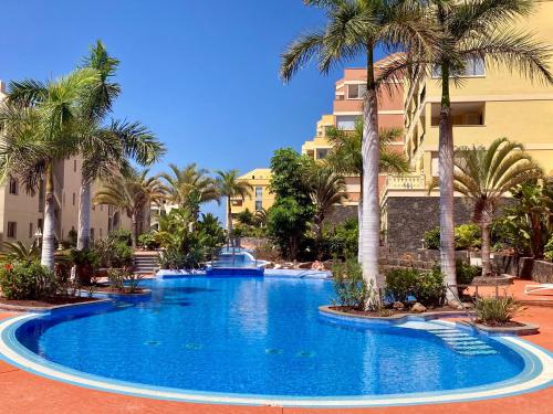 a large swimming pool with palm trees in a resort at Well refined apartment - stunning pool in Palm-mar