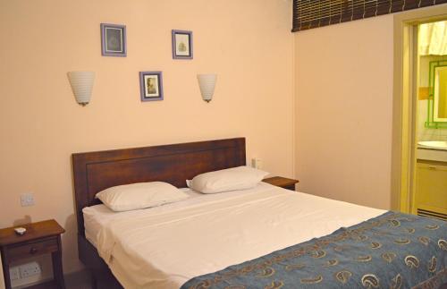 a bedroom with a bed with white sheets and pictures on the wall at Maurer Loisirs Ltee in Trou aux Biches