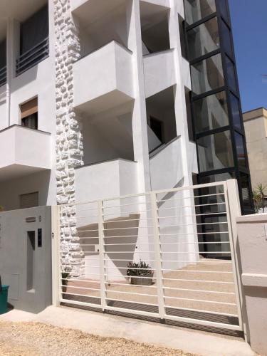 a white building with a staircase in front of it at Skyandsand Alghero in Alghero