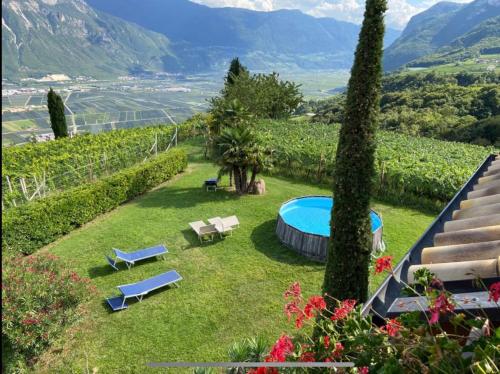 a garden with a pool and chairs and mountains at Santlhof - Sauvignon in Cortaccia