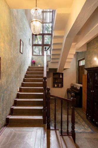 a staircase in a house with a chandelier at SaffronStays Thalassea, Alibaug - picturesque sea-facing villa with colonial decor in Alibaug