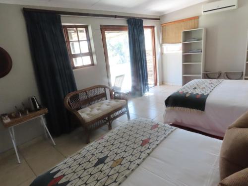 a bedroom with a bed and a chair and window at Sunset Lodge & Safaris in Guernsey Nature Reserve