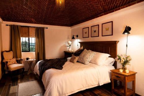 a bedroom with a large bed and a chair at Casa Aurora, estilo rústico-moderno, Guanajuato in Guanajuato
