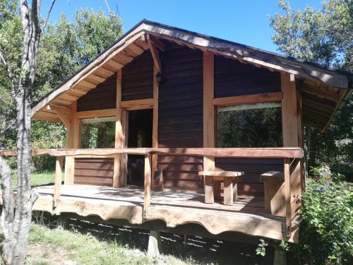 a log cabin with a porch and windows at Cabañas Rústicas Pucón Río Trancura in Pucón