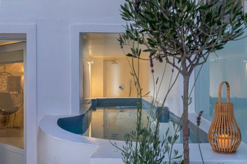 a swimming pool in a house with a tree at Pearl on the Cliff Hotel & Suites by Pearl Hotel Collection in Imerovigli
