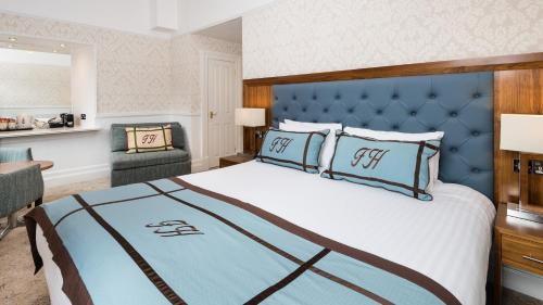 a bedroom with a large bed with a blue headboard at Fisher's Hotel in Pitlochry