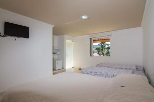 Pouso da Soraya في ريو دي كونتاس: غرفة نوم بيضاء مع سرير كبير ونافذة