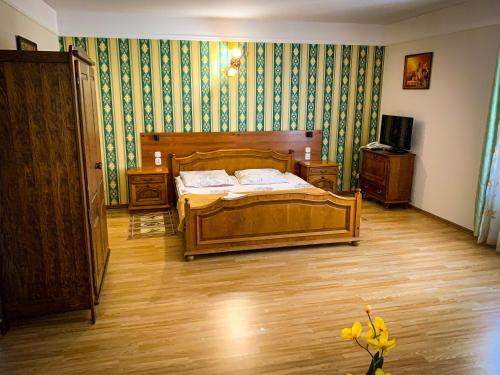 a bedroom with a wooden bed and green wallpaper at Hotel Wellness & SPA Antyczny Dwór in Rudna Mała
