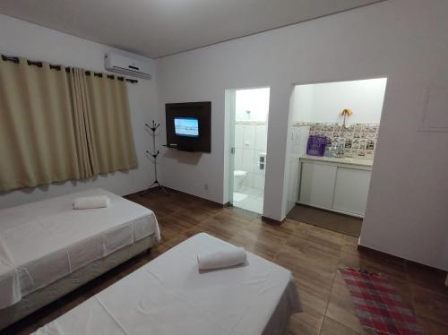 a white room with a bed and a tv and a room with at Flat Pinheirinho in Capitólio