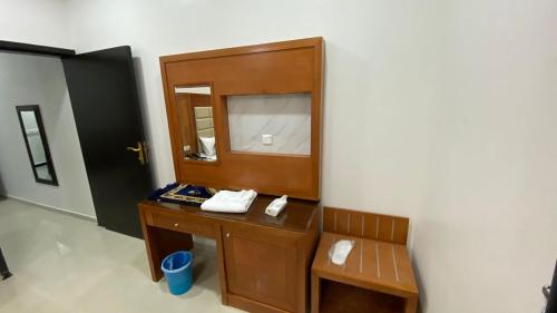 a bathroom with a wooden vanity with a chair and a mirror at الرؤية للشقق المخدومة - إقتصادي - Alruwyah For Serviced Apartments - Economy in Najran
