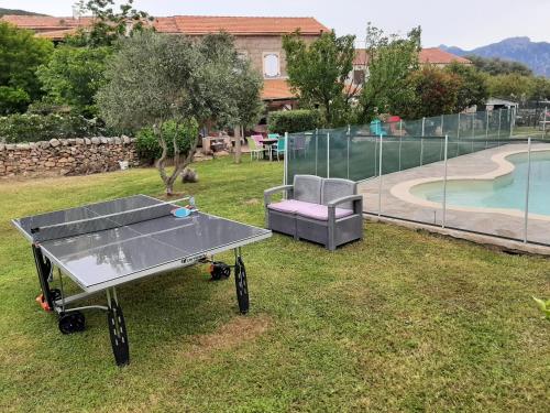 a ping pong table and a chair in a yard at Orasi Sartène Chalet Casa Fiurita in Sartène