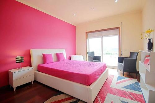 エシュポゼンデにあるCasa com piscina para 10 pessoas - 5 min da praia Esposendeのピンクのベッドルーム(ベッド1台、窓付)
