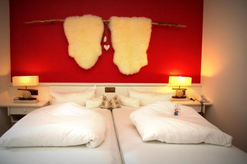 a bedroom with a bed with white pillows and a red wall at Alpenhotel Stefanie in Mayrhofen