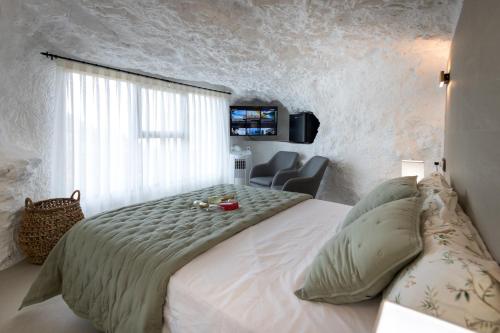 a bedroom with a large white bed and a chair at Casa túnel Nido de Águilas in Alcalá del Júcar