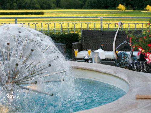 una fuente en medio de una piscina con una mesa en Hotel Ferienwohnungen Gabriel, en Keutschach am See