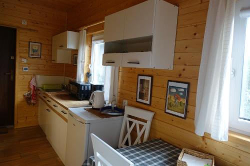 a kitchen with wooden walls and white cabinets and a table at Agroturystyka Bogdanki in Stary Targ