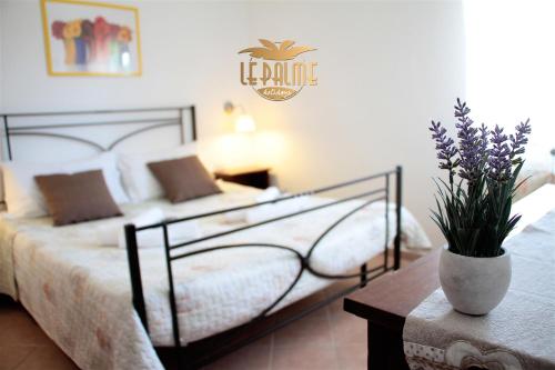 a bedroom with a bed and a vase with flowers on a table at Le Palme Holidays in Palmadula