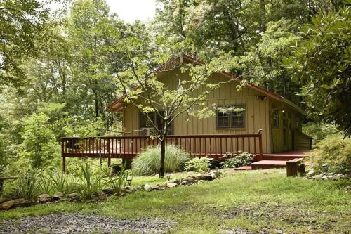 a small house with a deck in the woods at Fox Trot Cabin in Meadows of Dan