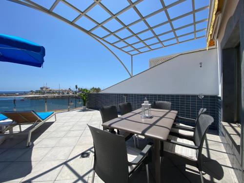 a patio with a table and chairs and a pool at Billy's Beachfront Apartment with pool access in Puerto de Mogán