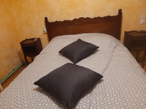 Una cama con dos almohadas negras encima. en la petite maison bleue, en Jugon Les Lacs
