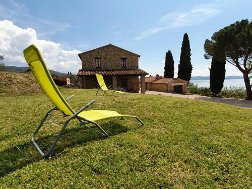 two chairs sitting in the grass in front of a house at Antico Casale Tiravento in Passignano sul Trasimeno