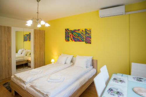 een slaapkamer met een groot bed met een gele muur bij Otthon-Laksz apartman in Nyíregyháza
