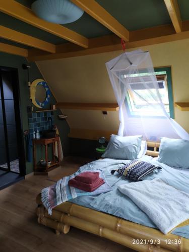 een slaapkamer met een groot bed en een raam bij Oeroeboeroe in Roderesch