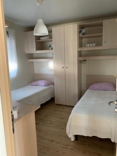 Habitación pequeña con 2 camas y armarios en Appartamento Cottage Lilla a 150 mt dal mare en Borgo Sabotino