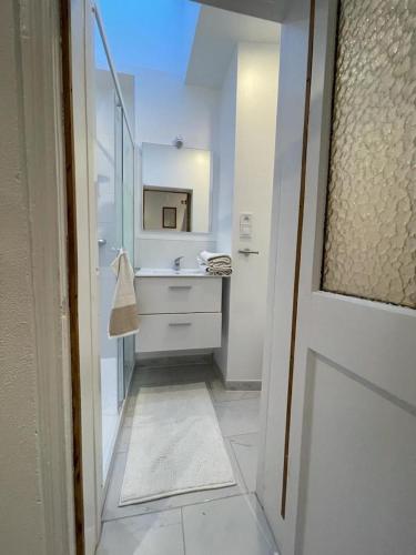 une salle de bain blanche avec un lavabo et un miroir dans l'établissement Le cottages des remparts - le lodge, à Boulogne-sur-Mer