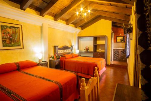 a bedroom with two beds in a room with a table at Hotel Maya Ik' in Antigua Guatemala