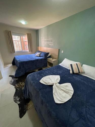 a bedroom with two beds with blue sheets with a bow on them at Pousada Pinhão e Poesia in Canela