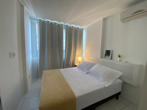 a white bedroom with a bed and a window at Apartamento The garden in Manhattan home service in Caruaru