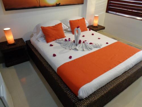 a bed with an orange and white comforter and two candles at Terrazas de San Agustin Hotel in San Agustín