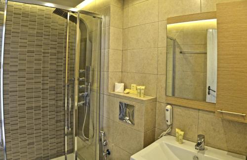 a bathroom with a shower and a sink and a mirror at Princess Irini Sea Front ApartHotel in Rethymno