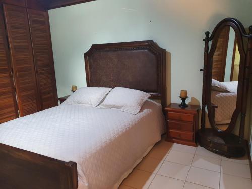 1 dormitorio con 1 cama grande y espejo en Casa Condomínio com 04 quartos, 200 metros da Praia de Manguinhos, en Búzios