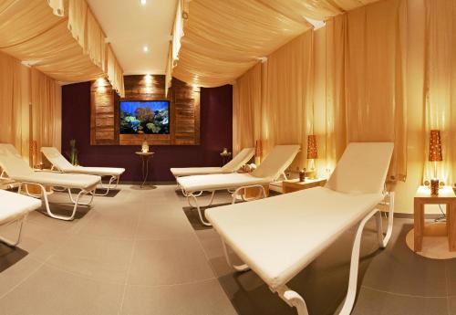 a waiting room with white chairs and a tv at Alpenhotel Stefanie - direkt buchbar in Mayrhofen