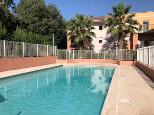 a swimming pool in front of a house with palm trees at Les Jardins des Senteurs - Appartement privé avec piscine et parking in Grasse