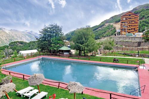 a large swimming pool with chairs and mountains in the background at Hotel Alto Nevados in Nevados de Chillan