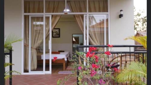 a room with a bed and a balcony with flowers at Fish Island Bungalows in Kampot