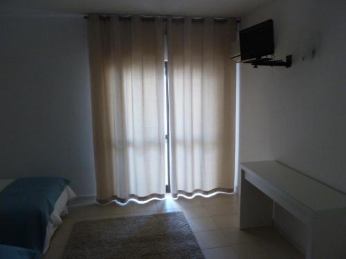 a bedroom with a bed and a window with curtains at Belo Horizonte in Luz