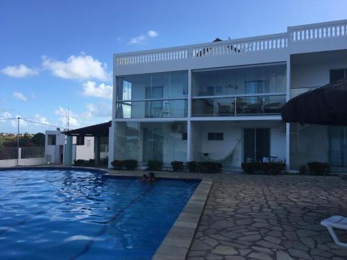 a building with a swimming pool in front of a building at Residencial Granito e Jasmim Flat em Jacumã vista para o Mar in João Pessoa