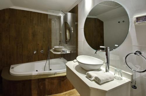 a bathroom with a sink and a tub and a mirror at Romano Hotel Boutique in Safed