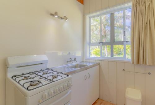 a white kitchen with a stove and a sink at Anson Bay Lodge in Burnt Pine