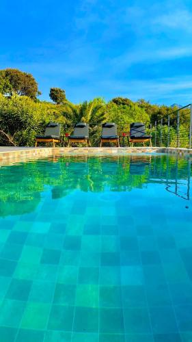 - une piscine avec deux chaises longues sur le côté du complexe dans l'établissement VILLA CORSA**** PISCINE VUE MER PANORAMIQUE, à Santa-Reparata-di-Balagna